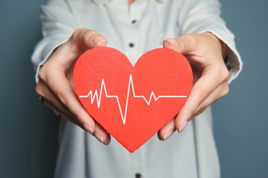 Woman holding red heart with cardiogram, closeup 