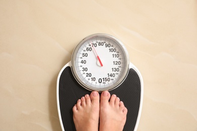 Woman standing on floor scales indoors, top view. Overweight problem