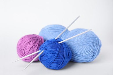 Soft woolen yarns and knitting needles on white background