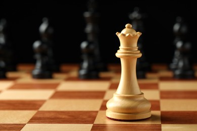 Chessboard with game pieces on black background, closeup. Space for text
