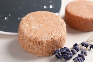 Solid shampoo bars and lavender flowers on white table, closeup