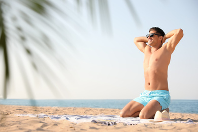 Happy man with slim body resting on beach. Space for text