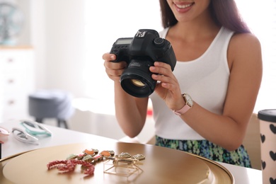 Photo of Young photographer taking picture of jewelry indoors, closeup