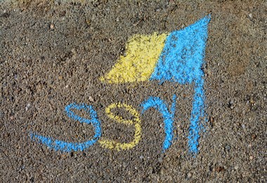 National flag of Ukraine with word Free drawn by blue and yellow chalk on asphalt, top view