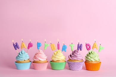 Birthday cupcakes with burning candles on pink background