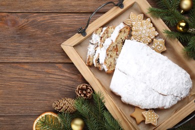 Traditional Christmas Stollen with icing sugar on wooden table, flat lay. Space for text