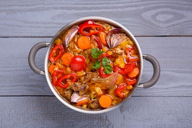 Photo of Saucepan of delicious vegetable soup with meat and ingredients on grey wooden table, top view