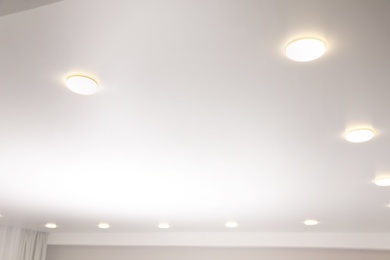 White stretch ceiling with spot lights in room, low angle view