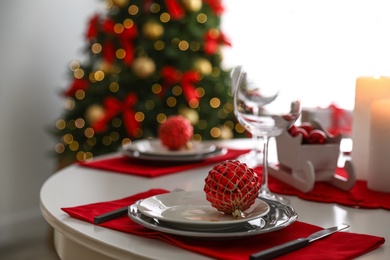 Festive table setting and Christmas tree in stylish room interior
