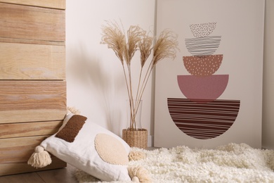 Vase with decorative dried plants and painting in stylish room interior
