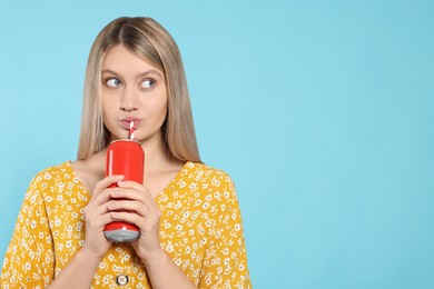 Photo of Beautiful woman drinking from red beverage can on light blue background. Space for text