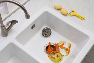 Vegetable scraps in kitchen sink with garbage disposal, above view