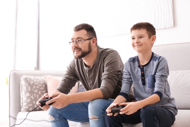 Little boy and his dad playing video game together at home