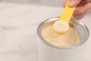 Woman with powdered infant formula at table, closeup and space for text. Preparing baby milk