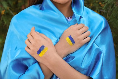 Woman with drawings of Ukrainian flag on hands outdoors, closeup