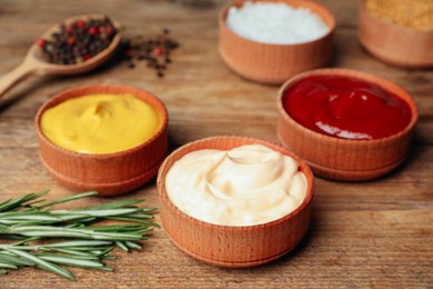Ketchup, mustard, mayonnaise and ingredients on wooden table