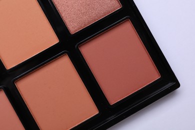 Photo of Colorful contouring palette on white background, closeup. Professional cosmetic product