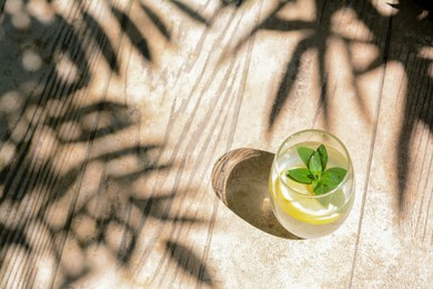 Photo of Refreshing water with lemon and mint on wooden table, space for text
