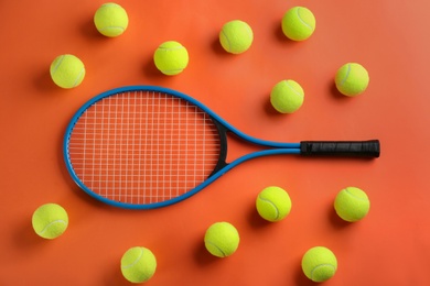 Tennis racket and balls on orange background, flat lay. Sports equipment