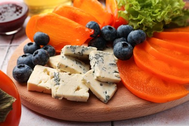 Photo of Delicious persimmon, blue cheese and blueberries on table, closeup