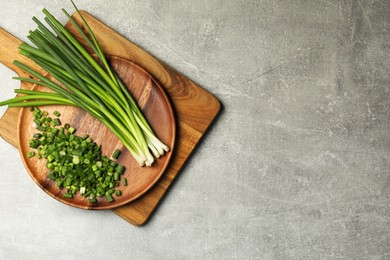 Chopped green spring onion and stems on grey table, top view. Space for text