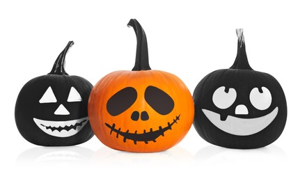 Photo of Halloween pumpkins with scary drawn faces on white background