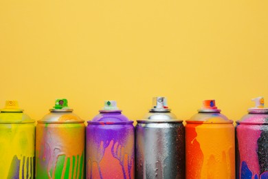 Used cans of spray paints on beige background, flat lay with space for text. Graffiti supplies