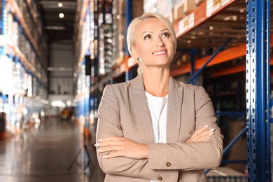 Photo of Happy manager in warehouse with lots of products. Space for text