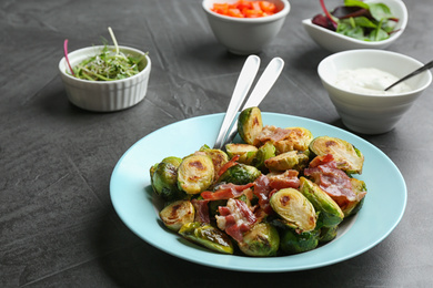 Delicious roasted Brussels sprouts with bacon served on black table