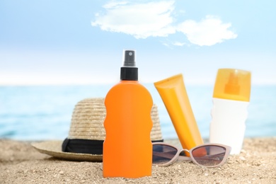 Composition with bottles of sun protection body cream on beach, space for design