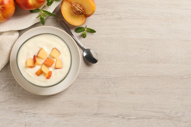 Delicious yogurt with fresh peach on light wooden table, flat lay. Space for text