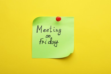 Photo of Paper note with words Meeting on Friday pinned to yellow background