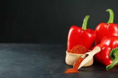 Paprika powder and fresh bell peppers on black table. Space for text