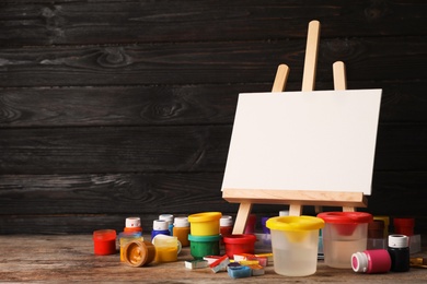 Set of painting materials for child on table near wooden wall. Space for text