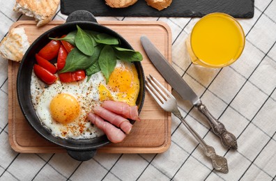 Delicious fried eggs with spinach, tomatoes and ham served on table, flat lay
