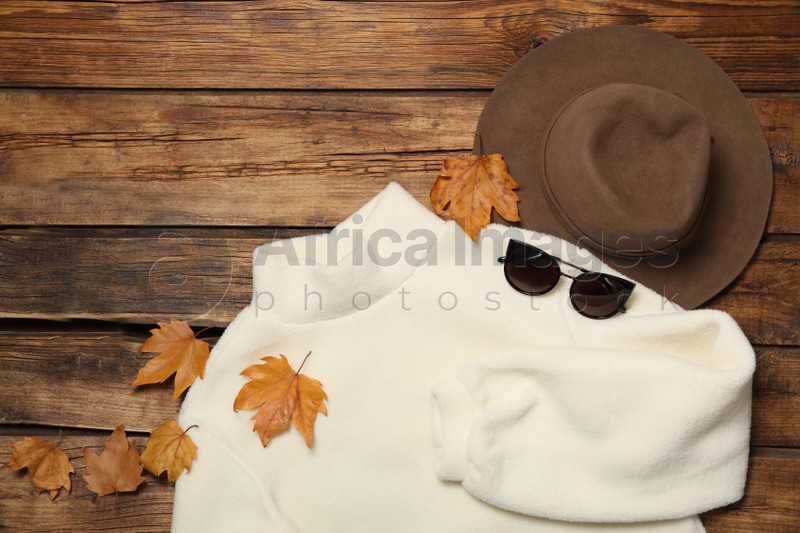 Photo of Flat lay composition with sweater and dry leaves on wooden background. Autumn season