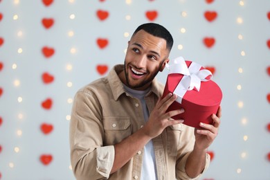 Photo of Handsome man with gift box indoors, view from camera. Valentine's day celebration in long distance relationship