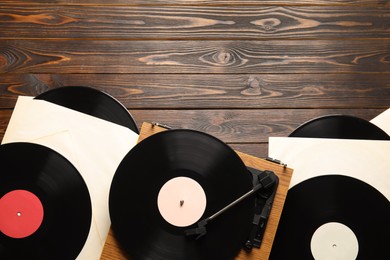 Vintage vinyl records and turntable on wooden background, flat lay. Space for text