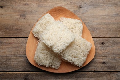 Photo of Plate with uncooked rice noodles on wooden table, top view