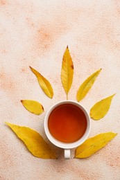 Autumn leaves and cup of tasty tea on color background, flat lay