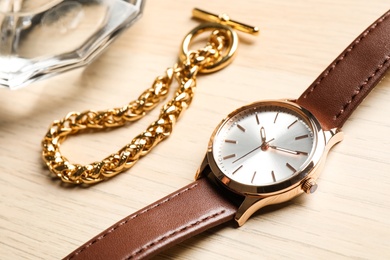 Luxury wrist watch and gold bracelet on wooden background, closeup