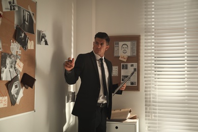 Detective looking at evidence board in office