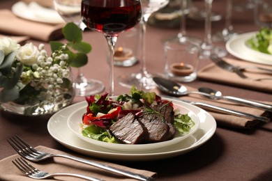Photo of Delicious grilled meat with vegetables and wine served on table in restaurant