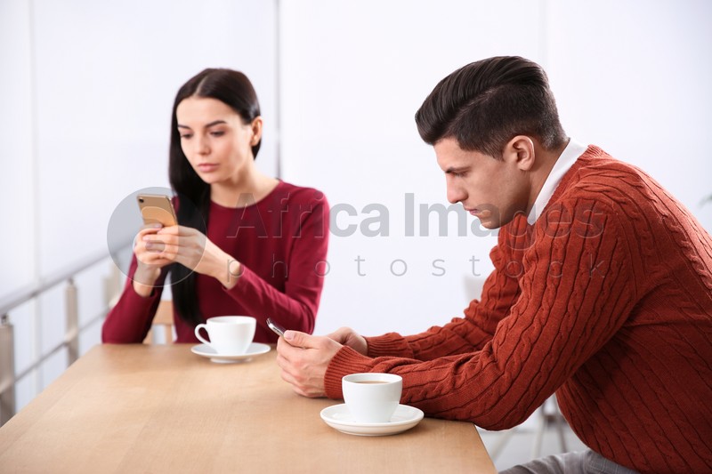 Couple addicted to smartphones ignoring each other in cafe. Relationship problems
