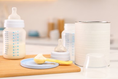 Feeding bottle with infant formula and powder on white table indoors