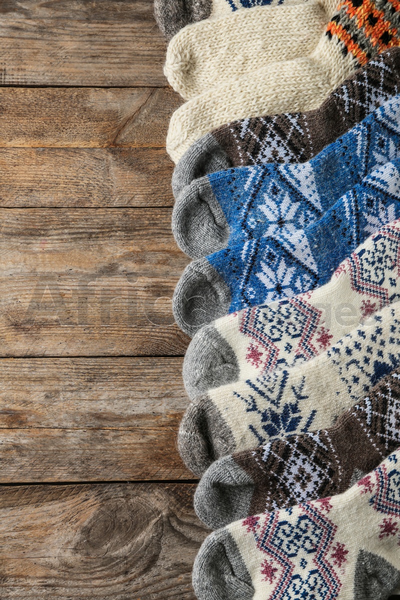 Different knitted socks on wooden background, flat lay with space for text. Winter clothes