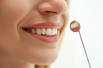 Examining patient's teeth on light background, closeup. Cosmetic dentistry
