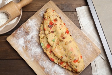 Unbaked Stollen with candied fruits and raisins on wooden table, flat lay