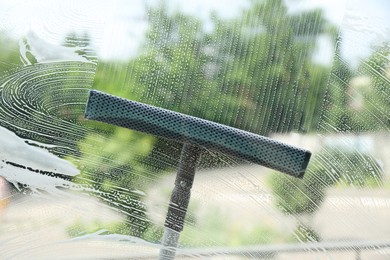 Washing window with squeegee from outside, view through glass