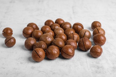 Photo of Delicious organic Macadamia nuts on white textured table